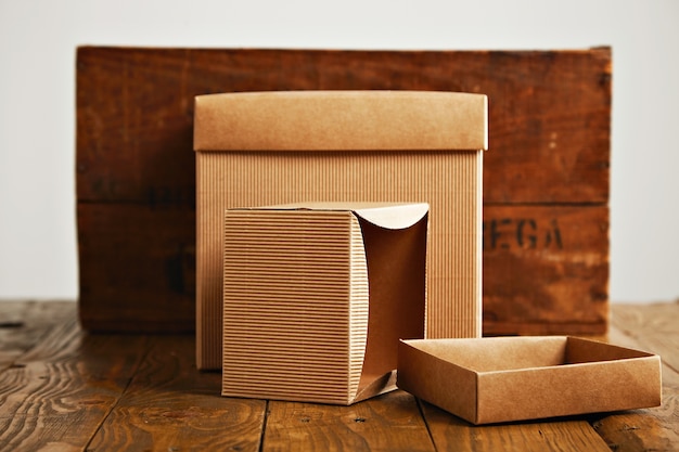 Un ouvert et un fermé des boîtes en carton beige à côté d'une caisse en bois brun rustique isolated on white