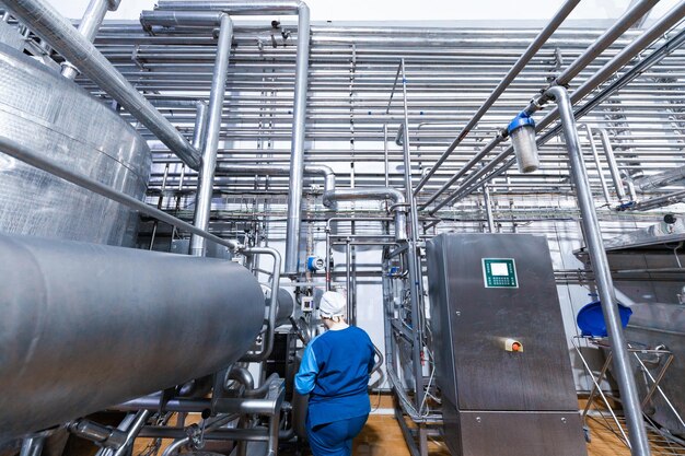Un ouvrier du département de production prépare la ligne tout en se tenant près de l'équipement de l'usine laitière