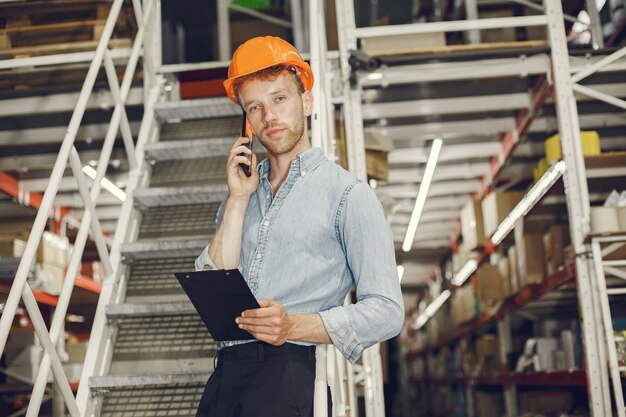 Ouvrier industriel à l'intérieur en usine. Homme d'affaires avec un casque orange. Homme en chemise bleue.