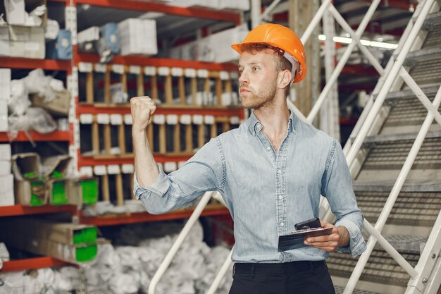 Ouvrier industriel à l'intérieur en usine. Homme d'affaires avec un casque orange. Homme en chemise bleue.