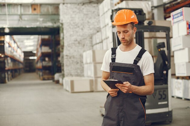 Ouvrier industriel à l'intérieur en usine. Jeune technicien avec casque orange.