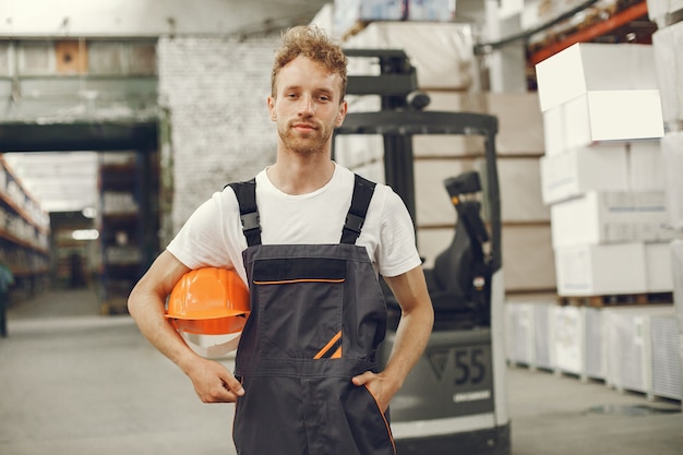 Ouvrier industriel à l'intérieur en usine. Jeune technicien avec casque orange.