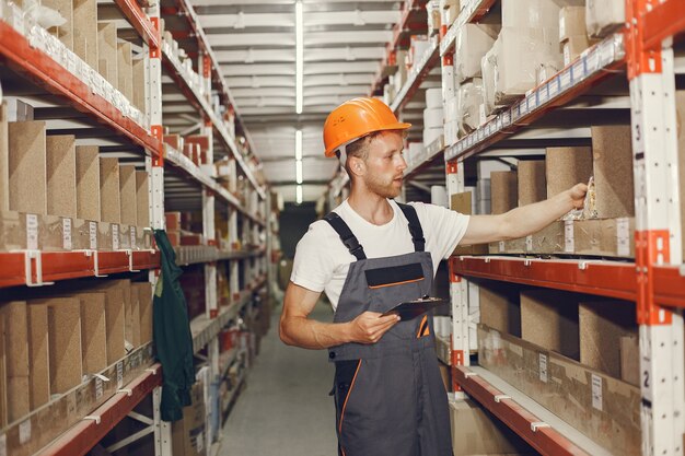 Ouvrier industriel à l'intérieur en usine. Jeune technicien avec casque orange.