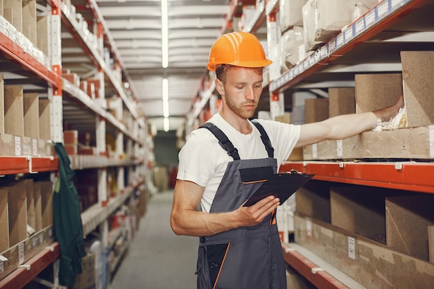 Ouvrier industriel à l'intérieur en usine. Jeune technicien avec casque orange.