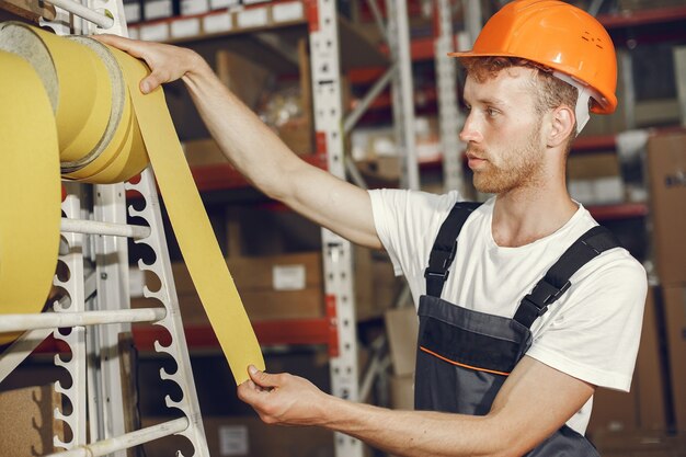 Ouvrier industriel à l'intérieur en usine. Jeune technicien avec casque orange.