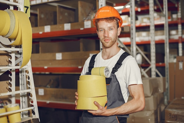 Ouvrier industriel à l'intérieur en usine. Jeune technicien avec casque orange.