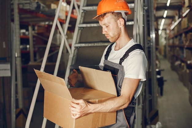 Ouvrier industriel à l'intérieur en usine. Jeune technicien avec casque orange.