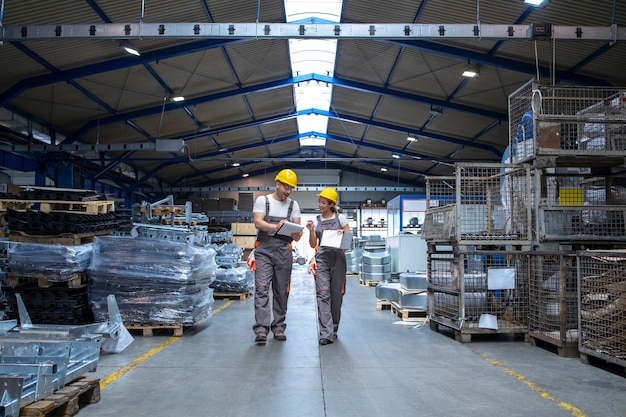 Ouvriers de l'usine marchant dans un grand hall de production et ayant une conversation