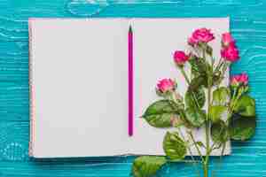 Photo gratuite ouvrir le livre avec crayon et violet fleurs