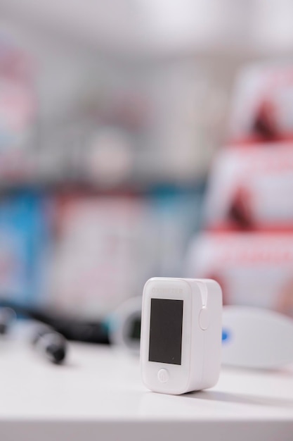 Photo gratuite oxymètre médical debout sur une table dans une pharmacie vide prête à être utilisée par le client, appareil numérique pour mesurer la saturation en oxygène. pharmacie remplie de médicaments, de vitamines et de produits pharmaceutiques