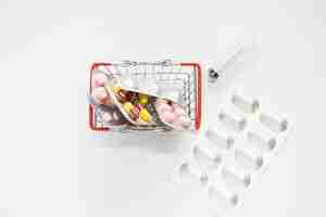 Photo gratuite pack de pilules médicinales en panier miniature avec seringue sur fond blanc
