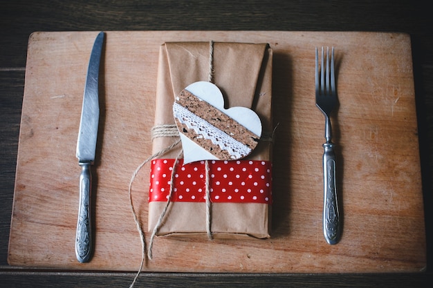 Photo gratuite package brown avec un coeur et l'argenterie sur les côtés