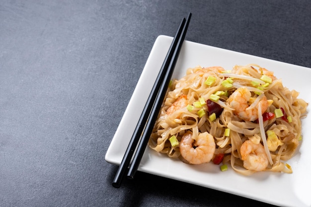 Photo gratuite pad thai aux crevettes et légumes sur fond d'ardoise noire