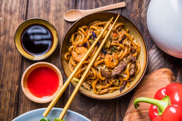 Pad thaï avec des légumes; Gambas et boeuf à la sauce soja sur table en bois