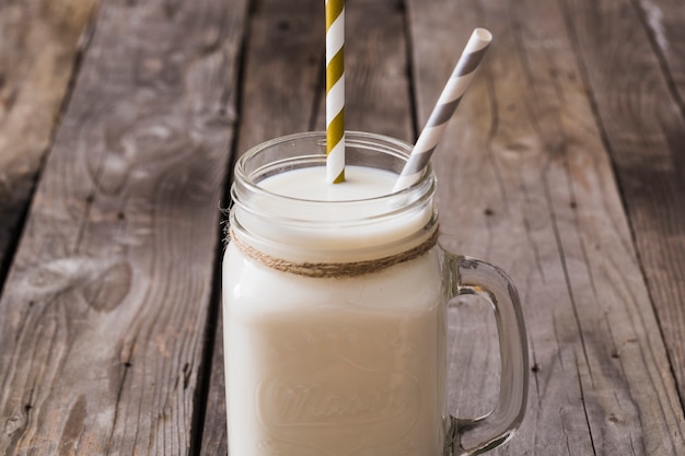 Pailles rayées dans le pot de lait sur la table en bois