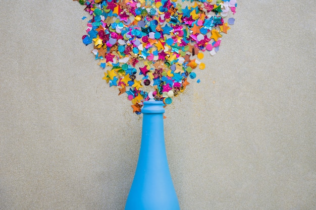 Paillettes dispersées de la bouteille bleue sur la table grise