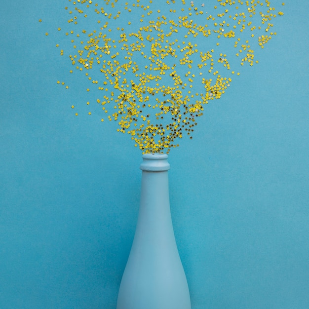 Paillettes dispersées de la bouteille bleue sur la table