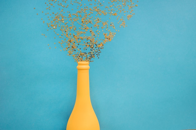 Paillettes dispersées de la bouteille sur la table bleue