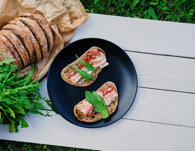 Pain au jambon et herbes sur une plaque noire sur une table en bois.