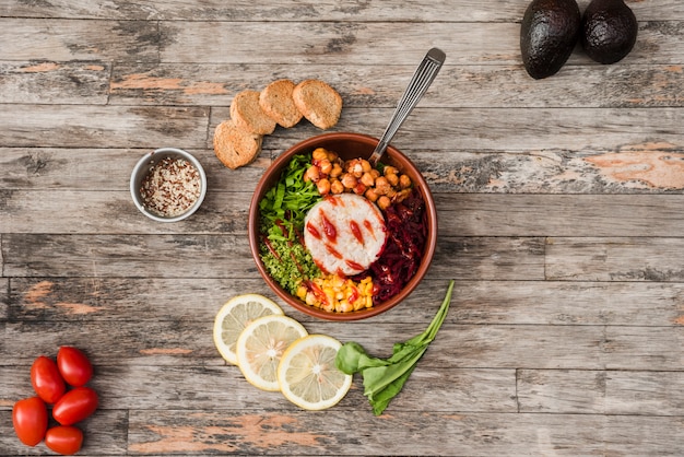 Pain; citron; tomates et avocat avec bol à burrito sur le bureau en bois