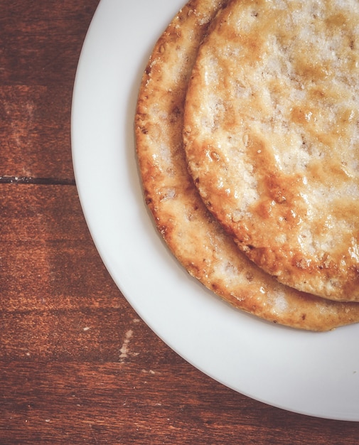 Photo gratuite pain croustillant dans une assiette blanche sur une surface en bois