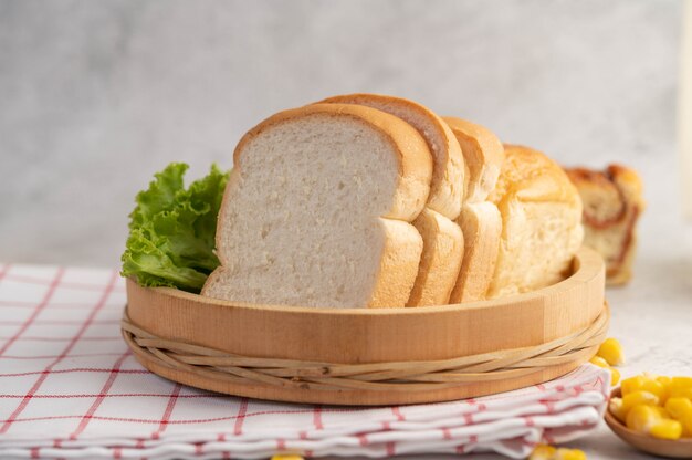 Pain dans un plateau en bois sur un tissu rouge et blanc.