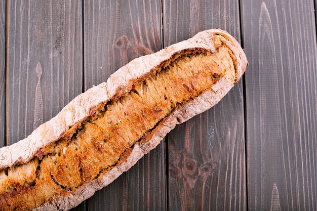 Photo gratuite le pain entier se trouve sur une table de bois sombre