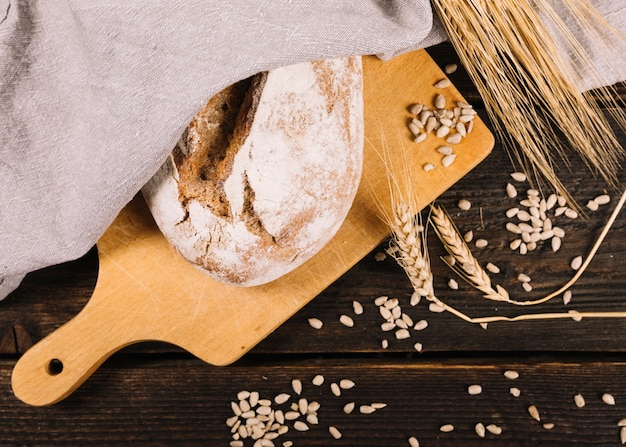 Pain et épi de blé avec des graines de tournesol sur une table en bois foncée