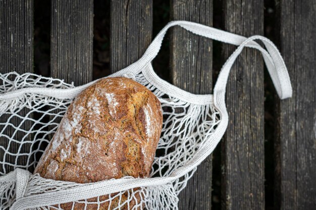 Pain frais dans un sac à provisions sur un fond plat en bois