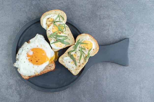 Pain grillé avec oeuf au plat sur tableau noir.