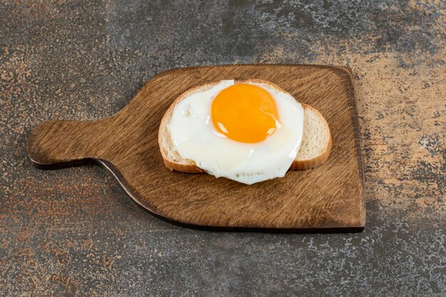 Pain grillé avec oeuf sur planche de bois.