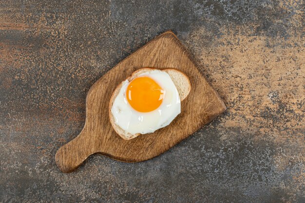 Pain grillé avec oeuf sur planche de bois.