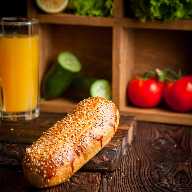 pain à hot dog avec jus d'orange et concombres et tomate et laitue en planche de bois