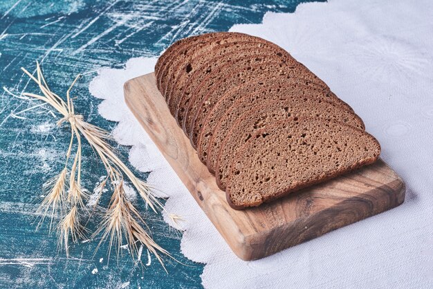 Pain noir sur une planche de bois sur table bleue.