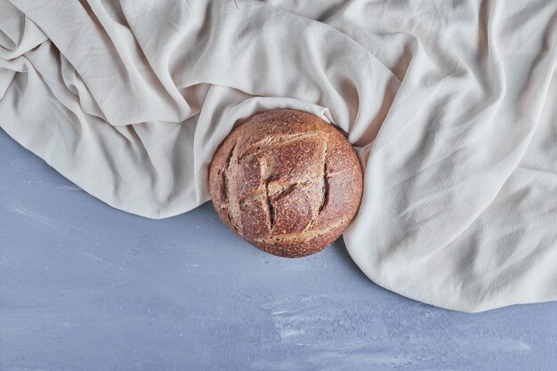 Pain de pain rond fait à la main sur une nappe grise.