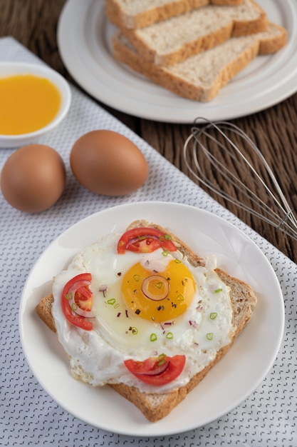 Pain placé avec un œuf au plat avec des tomates, de la farine de tapioca et des oignons de printemps tranchés.