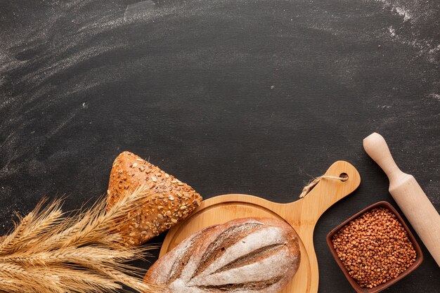 Pain sur planche de bois et rouleau à pâtisserie avec du blé