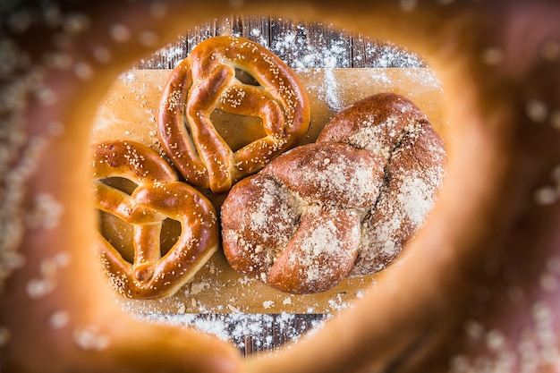 Pain tressé et bretzels sur planche à découper vus à travers des bagels