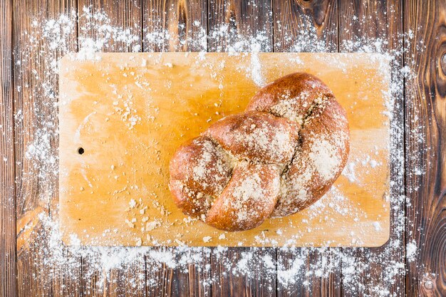 Pain tressé sur planche à découper avec farine blanche