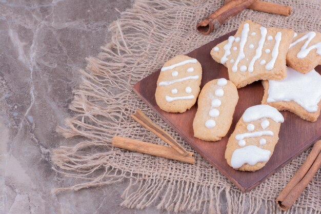 Pains d'épices de Noël en formes ovales et étoiles sur une planche de bois avec des bâtons de cannelle autour