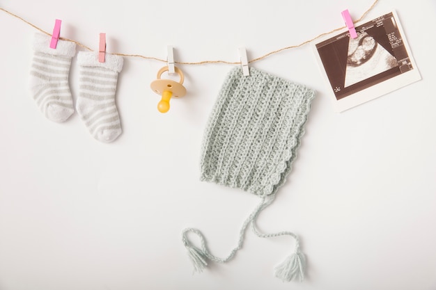 Une paire de chaussettes; sucette; image de coiffe et sonographie suspendue à une ficelle avec une pince à linge