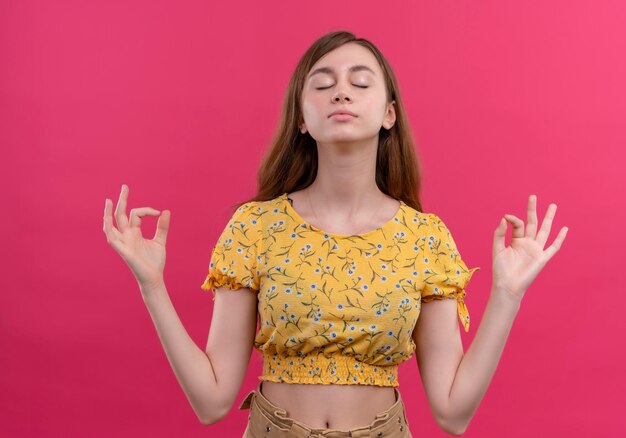 Paisible jeune fille faisant signe ok avec les yeux fermés sur un espace rose isolé