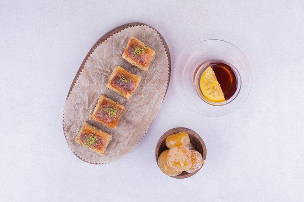 Pakhlava turc sur plateau en bois avec confiture et une tasse de thé.