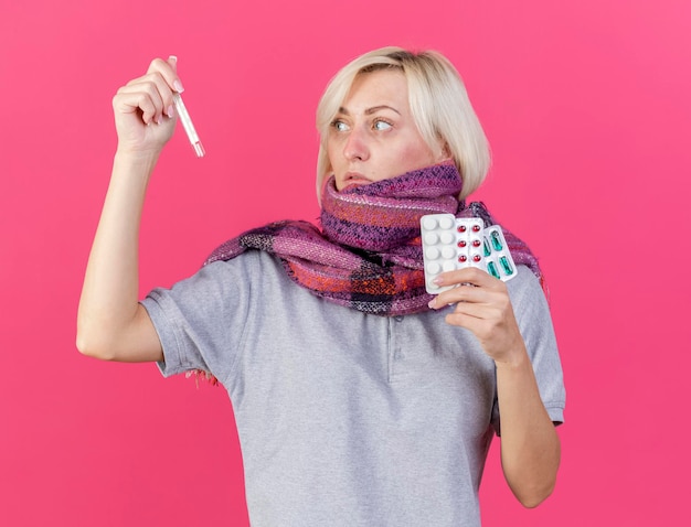 Pâle jeune blonde femme slave malade portant un foulard détient des paquets de pilules médicales