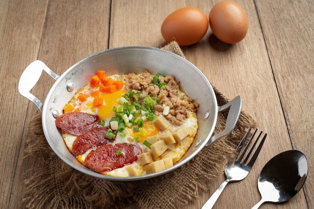 Pan oeufs saupoudrés de saucisse chinoise, bacon en dés, petit déjeuner.