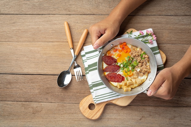 Pan oeufs saupoudrés de saucisse chinoise, bacon en dés, petit déjeuner.