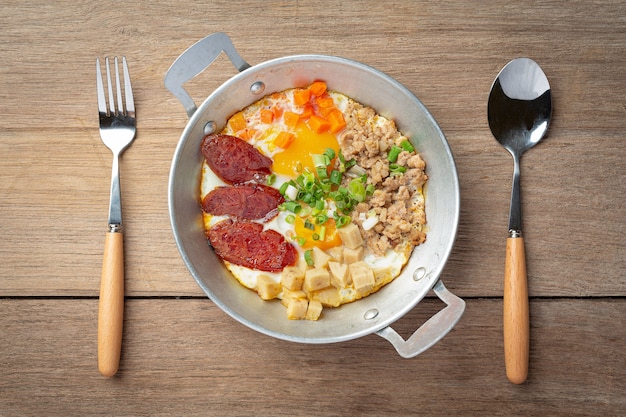 Pan oeufs saupoudrés de saucisse chinoise, bacon en dés, petit déjeuner.