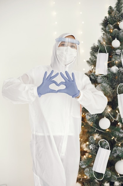 Photo gratuite pandémie de coronavirus covid-2019. combinaison de protection, lunettes, gants, masque. l'arbre de noël est décoré d'un masque médical.