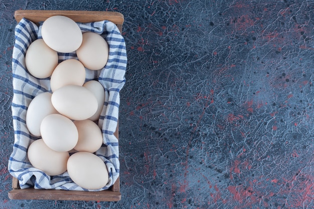 Photo gratuite un panier en bois avec des œufs de poule crus frais.