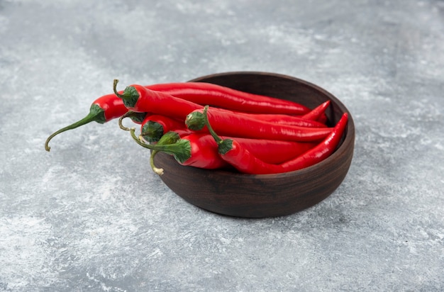 Panier en bois de piments rouges sur une surface en marbre.